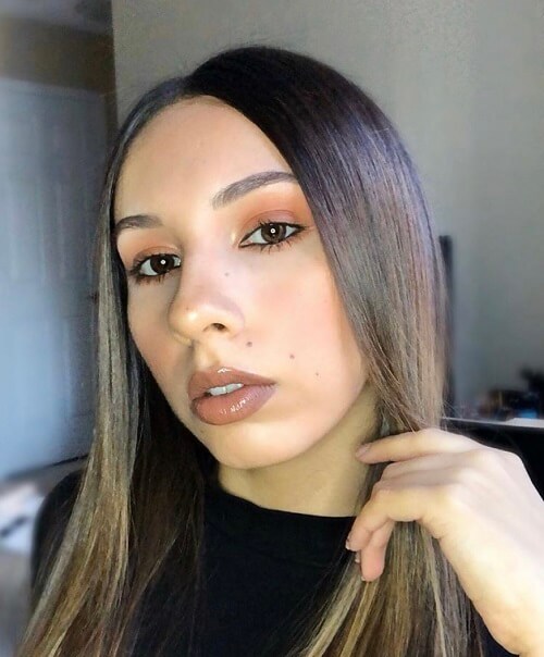 A woman displays a make-up look consisting of a neutral palette while brushing her hair from her face