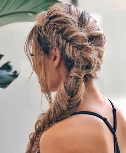 A full, double-sectioned fishtail braid cascades down a woman's shoulder
